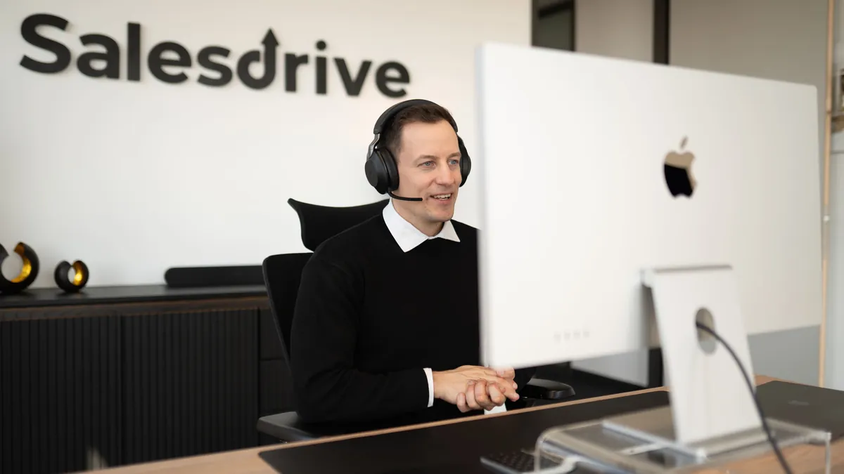 Alexander Kiraly mit Headset am Arbeitsplatz im SalesDrive-Büro in Wien